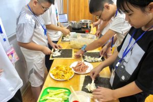 Hình ảnh các “đầu bếp nhí” đang làm món cơm cuộn trong hoạt động tại Culinary Camp 2023